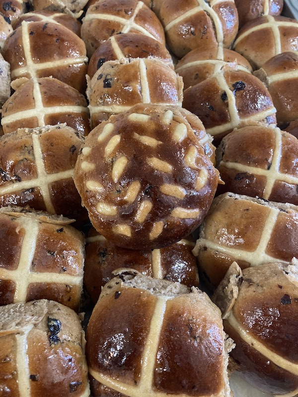 Some hot cross buns, the one in the middle has the Loaf logo instead of a cross