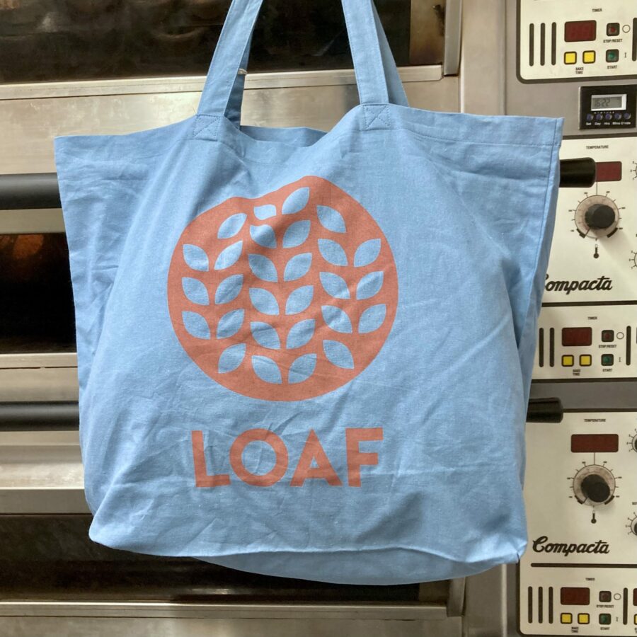 A blue tote bag with the Loaf logo