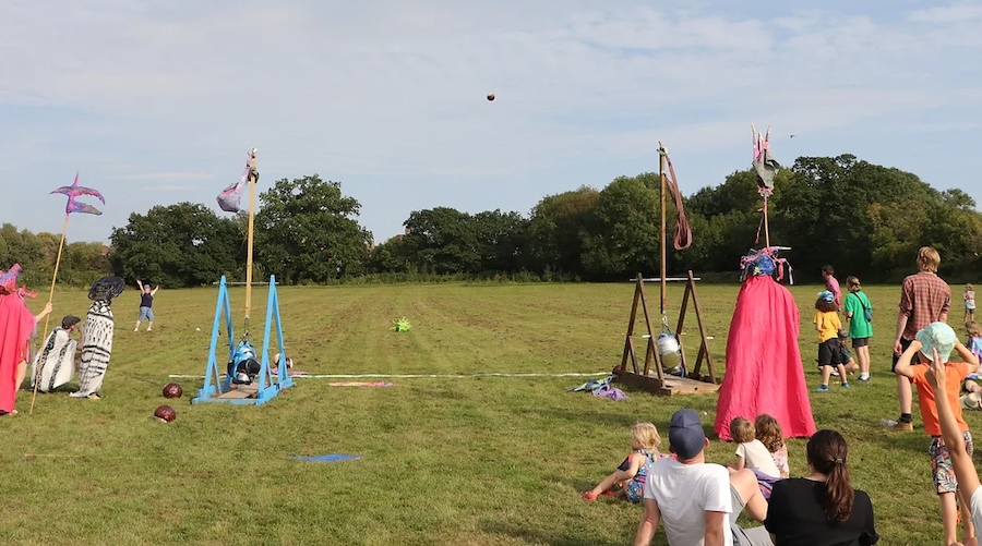 Two trebuchets in a park throwing papermache balls into the air.